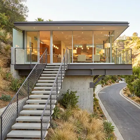 Modern glass house on a steep hillside with long concrete stairs