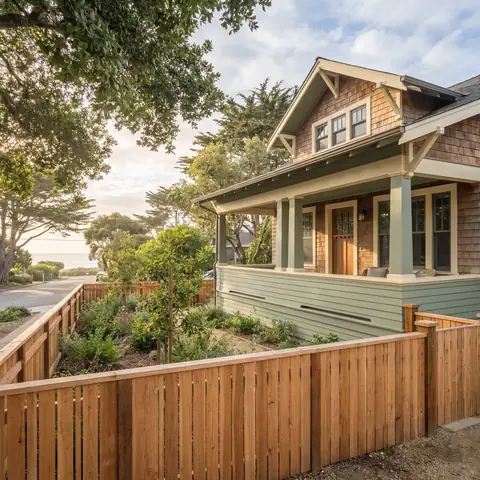 Craftsman-style house with a wood fence and a coastal garden