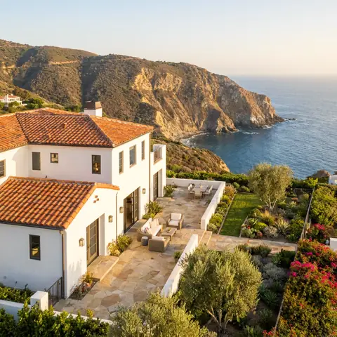 White Mediterranean house with a tile roof on a cliff above the ocean
